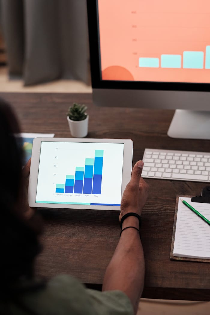 A person reviews statistical graphs on a tablet, showcasing data analysis and technology.